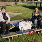 Jerri & her toy manchester terrier posing with friends & black poodle with a lot of CPE first place ribbons & a sweatshirt that says 'Prooftastics'